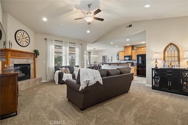 living area with visible vents, ceiling fan, light colored carpet, lofted ceiling, and a tile fireplace