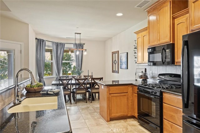 kitchen with visible vents, dark stone counters, a peninsula, a sink, and black appliances