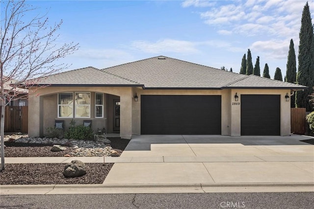 view of front facade with concrete driveway, fence, a garage, and stucco siding