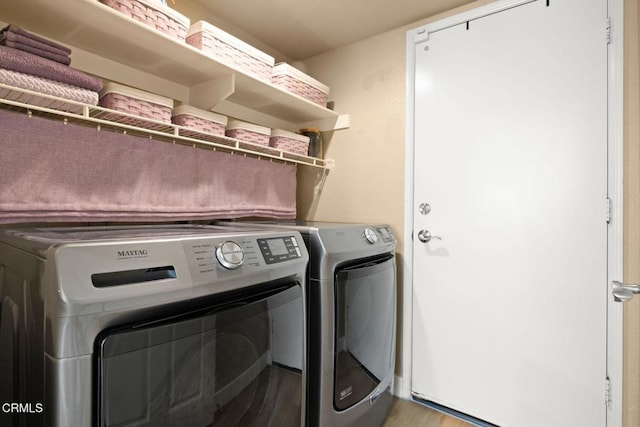 laundry room featuring washing machine and dryer, laundry area, and light wood-style flooring