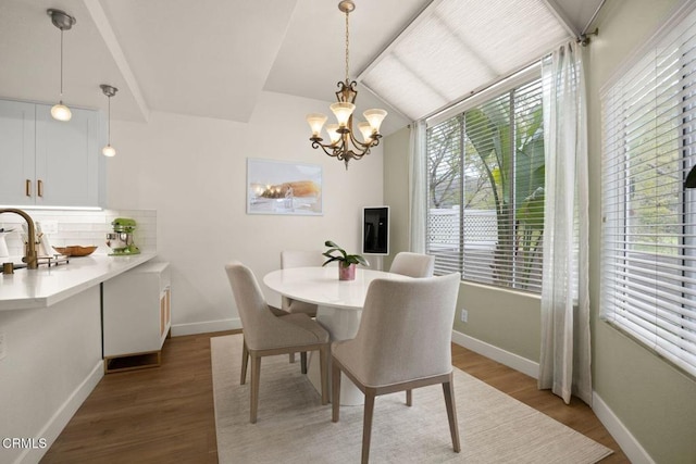 dining area with lofted ceiling, a notable chandelier, baseboards, and wood finished floors