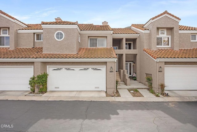 townhome / multi-family property featuring concrete driveway, a tiled roof, and stucco siding