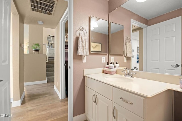 bathroom with vanity, wood finished floors, visible vents, and baseboards