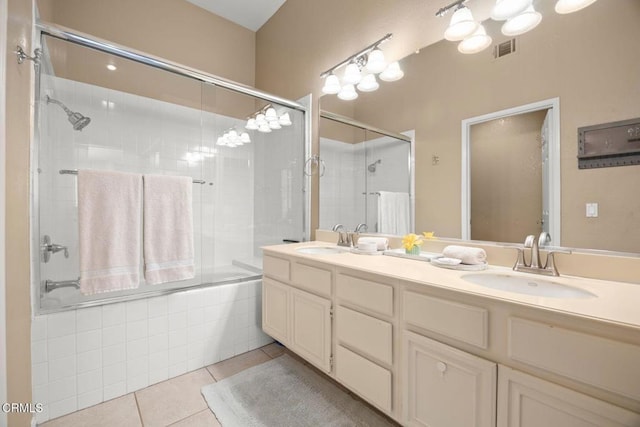 full bath featuring tiled shower / bath combo, double vanity, a sink, and tile patterned floors