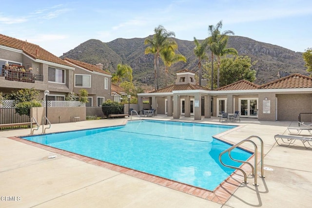 pool with a patio area, fence, a mountain view, and french doors