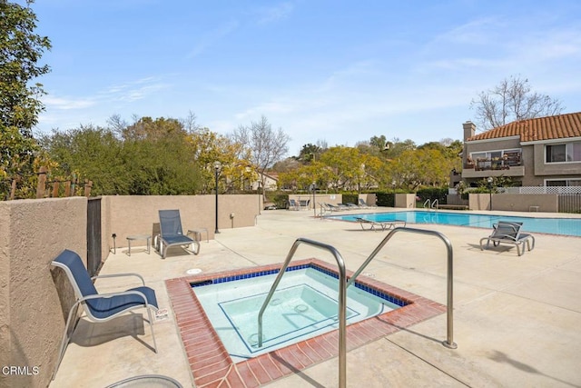 community pool with a community hot tub, fence, and a patio