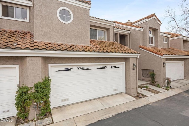 multi unit property with driveway, a tile roof, and stucco siding