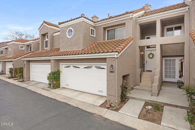 view of front of home featuring driveway, a tiled roof, and stucco siding