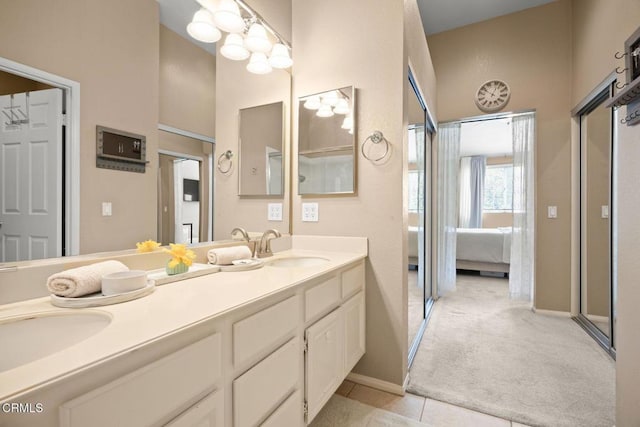 ensuite bathroom with double vanity, tile patterned floors, a sink, and connected bathroom