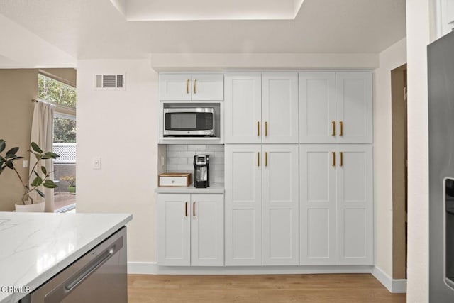 kitchen with tasteful backsplash, visible vents, appliances with stainless steel finishes, and light wood-style flooring