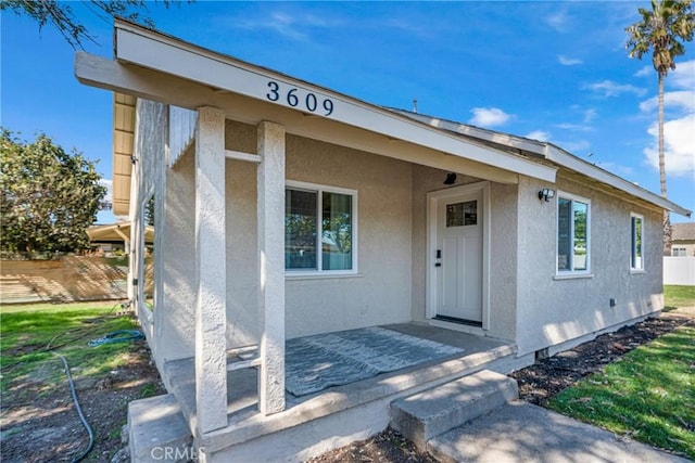 doorway to property with fence and stucco siding