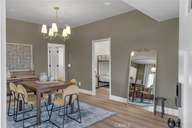 dining area featuring baseboards, arched walkways, wood finished floors, and a notable chandelier