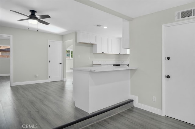 kitchen with white cabinetry, visible vents, baseboards, and wood finished floors