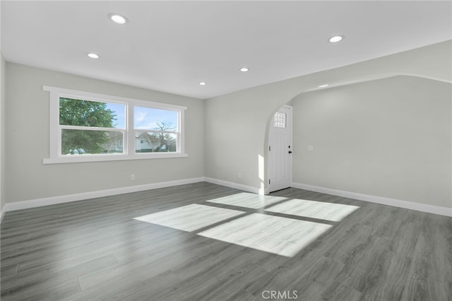 interior space featuring arched walkways, recessed lighting, baseboards, and wood finished floors