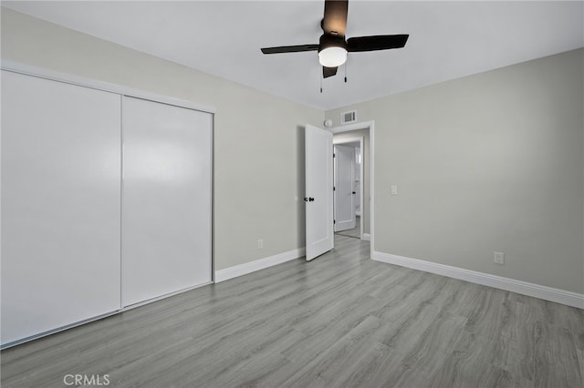 unfurnished bedroom with baseboards, visible vents, a ceiling fan, wood finished floors, and a closet