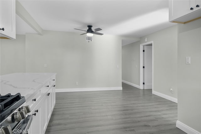 kitchen featuring ceiling fan, light wood-style flooring, white cabinetry, light stone countertops, and stainless steel gas stove