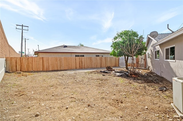 view of yard with central AC and a fenced backyard