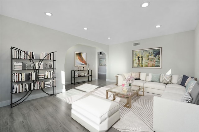 living area featuring arched walkways, wood finished floors, visible vents, and recessed lighting