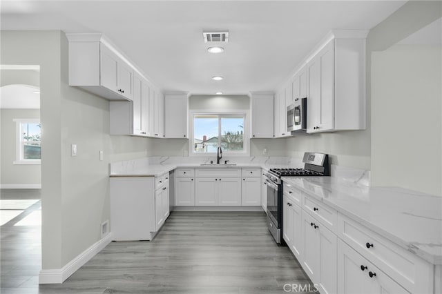 kitchen with stainless steel appliances, a sink, visible vents, and light stone countertops