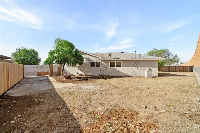 back of house featuring a fenced backyard, central AC, and stucco siding