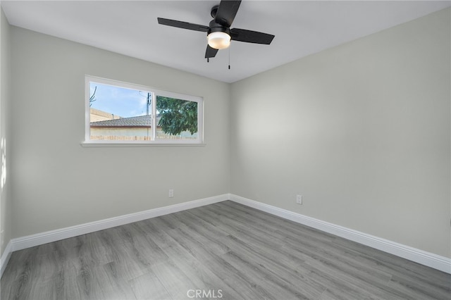 empty room featuring ceiling fan, baseboards, and wood finished floors