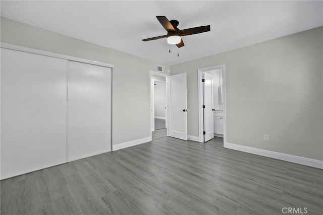 unfurnished bedroom with visible vents, baseboards, a ceiling fan, wood finished floors, and a closet