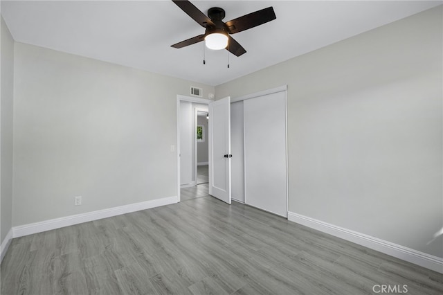 unfurnished bedroom featuring baseboards, visible vents, a ceiling fan, wood finished floors, and a closet