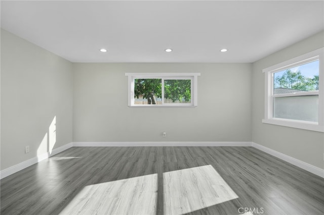 empty room featuring recessed lighting, wood finished floors, a wealth of natural light, and baseboards