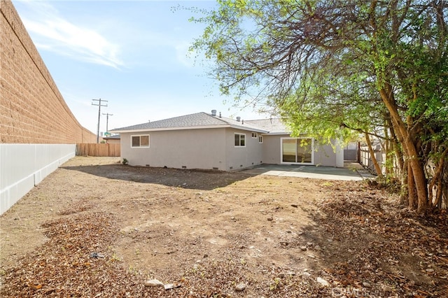 back of house featuring crawl space, a fenced backyard, a patio, and stucco siding