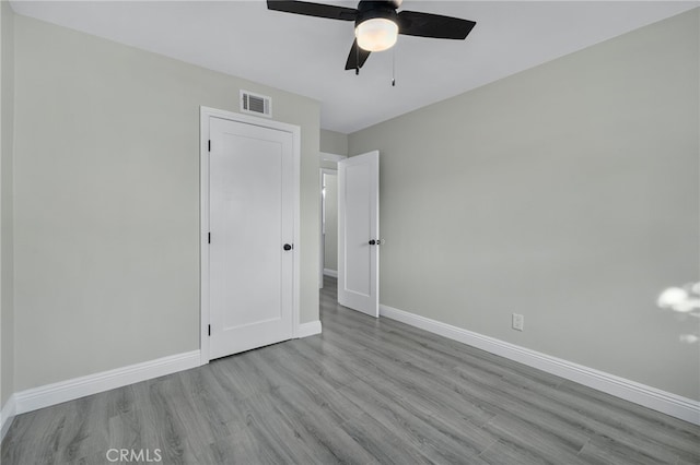 unfurnished bedroom with visible vents, ceiling fan, baseboards, and wood finished floors