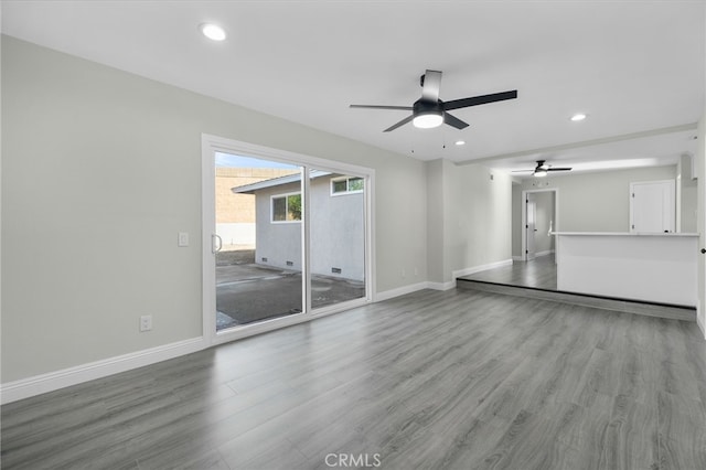 unfurnished living room with a ceiling fan, recessed lighting, baseboards, and wood finished floors