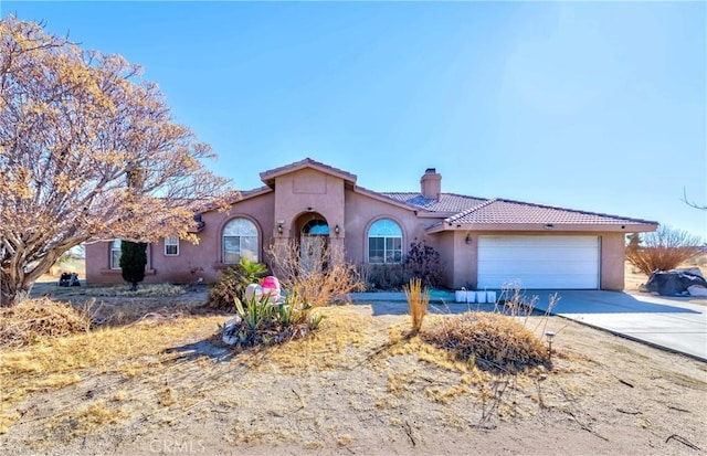 view of front facade with a garage, driveway, a chimney, and stucco siding