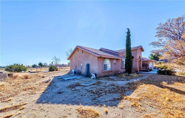 view of home's exterior with a tile roof and stucco siding