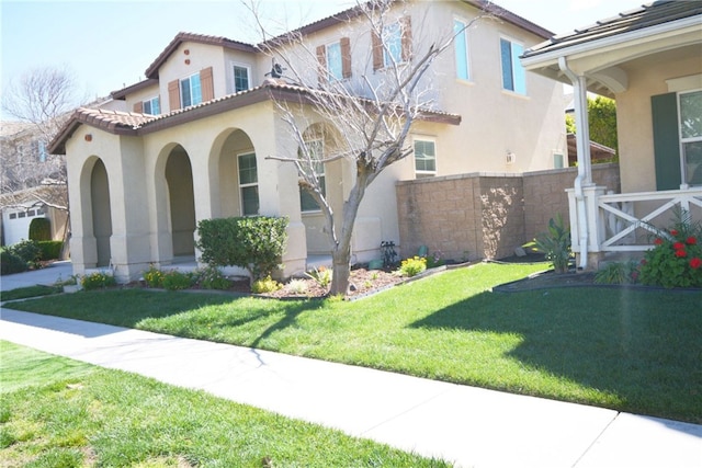 mediterranean / spanish house with stucco siding, a tiled roof, fence, and a front yard