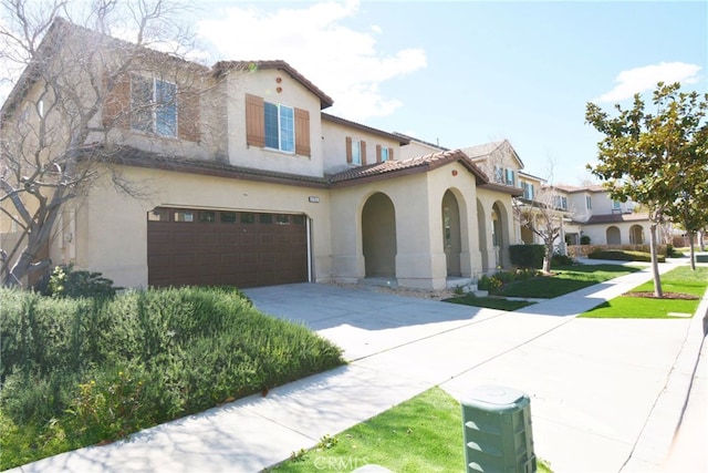 mediterranean / spanish house with a garage, a tile roof, driveway, and stucco siding