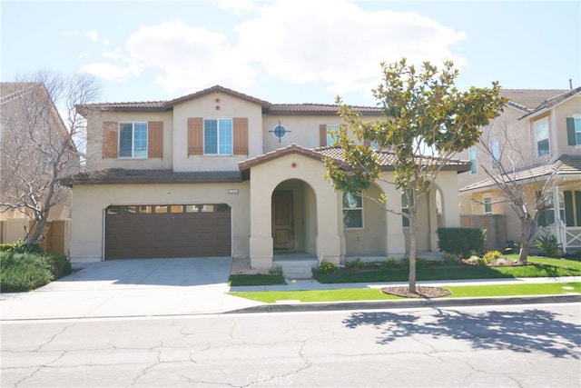 mediterranean / spanish-style home featuring a tile roof, driveway, an attached garage, and stucco siding