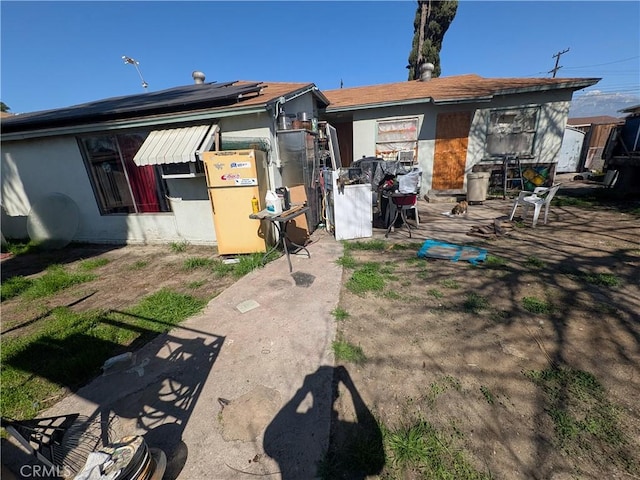 rear view of property with solar panels and stucco siding