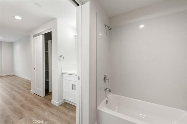 bathroom with recessed lighting, wood finished floors, vanity, baseboards, and tub / shower combination