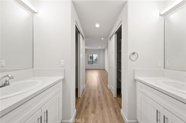 bathroom featuring two vanities, a sink, and wood finished floors