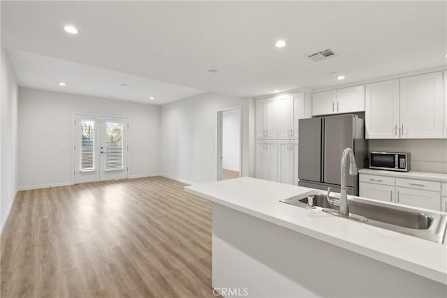 kitchen featuring stainless steel appliances, a sink, light countertops, and white cabinets