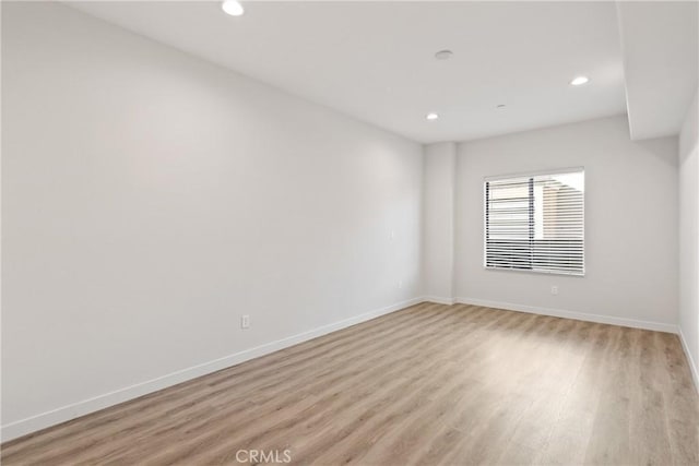 empty room with light wood-style flooring, baseboards, and recessed lighting