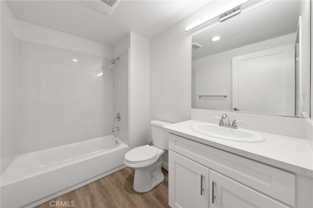 full bathroom with visible vents, toilet, wood finished floors, vanity, and shower / bathing tub combination