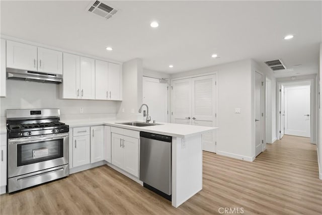 kitchen featuring under cabinet range hood, visible vents, appliances with stainless steel finishes, and a sink