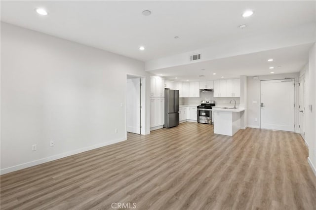 unfurnished living room featuring light wood-style flooring, visible vents, a sink, and recessed lighting