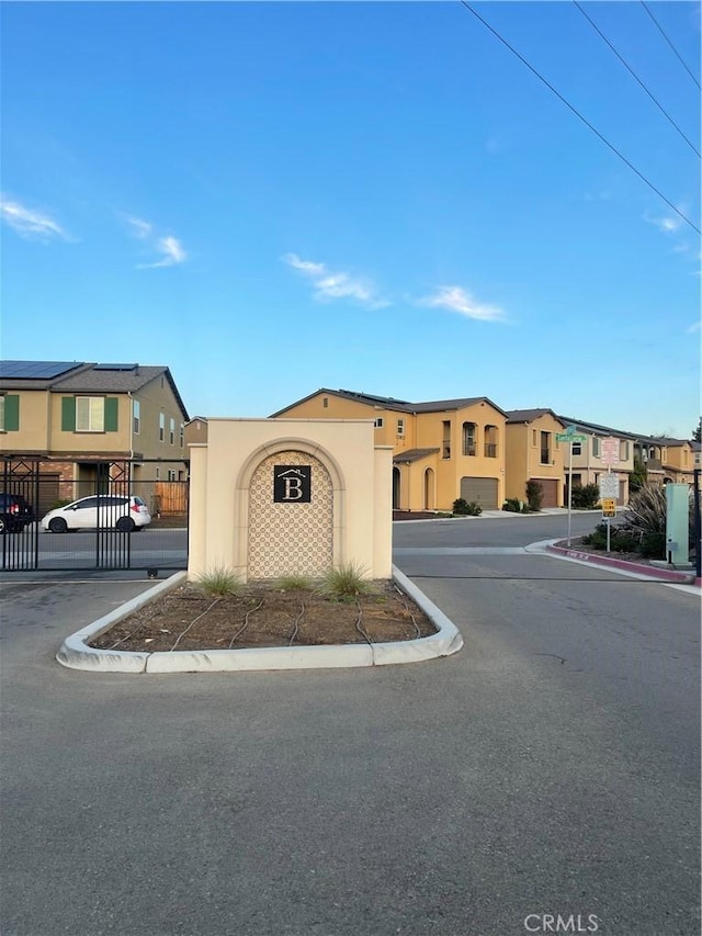 view of front facade with a residential view, a gate, fence, and stucco siding