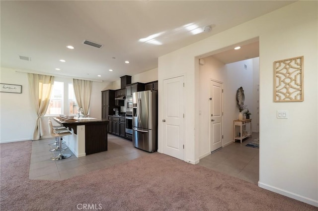 kitchen with stainless steel appliances, light colored carpet, visible vents, and a breakfast bar area