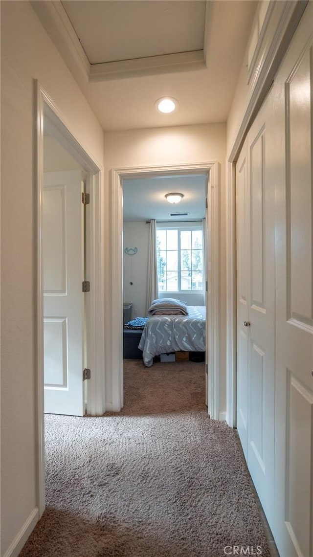 hall featuring carpet floors and a tray ceiling