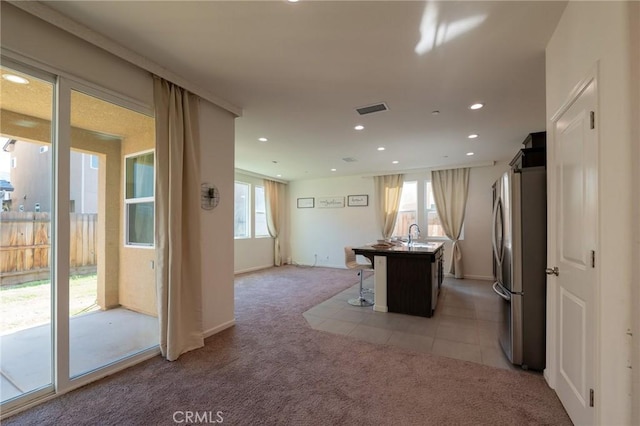 interior space with light carpet, visible vents, plenty of natural light, and freestanding refrigerator