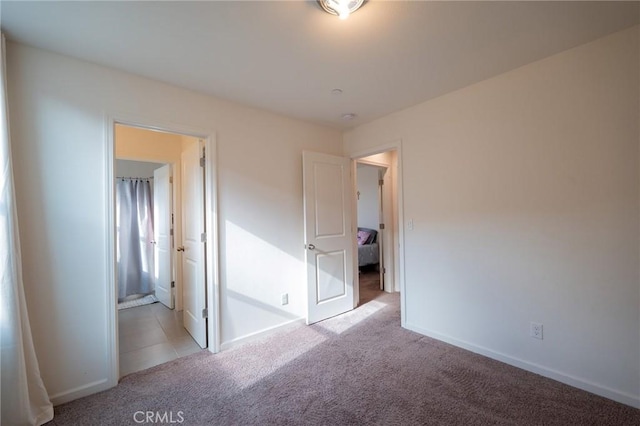 unfurnished bedroom featuring light carpet and baseboards