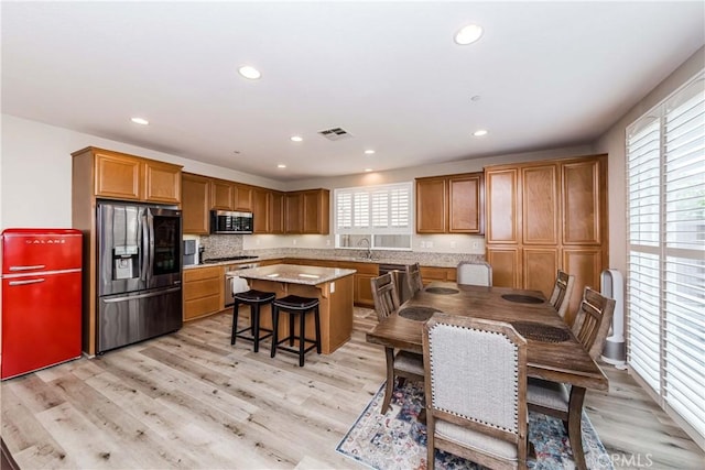 kitchen featuring light wood-type flooring, a kitchen island, visible vents, and stainless steel appliances